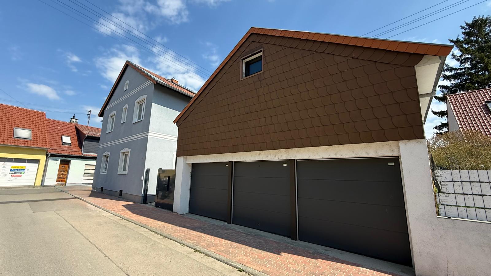 Straßenansicht mit drei Garagentoren und dem angrenzenden Zweifamilienhaus in Edingen-Neckarhausen.
